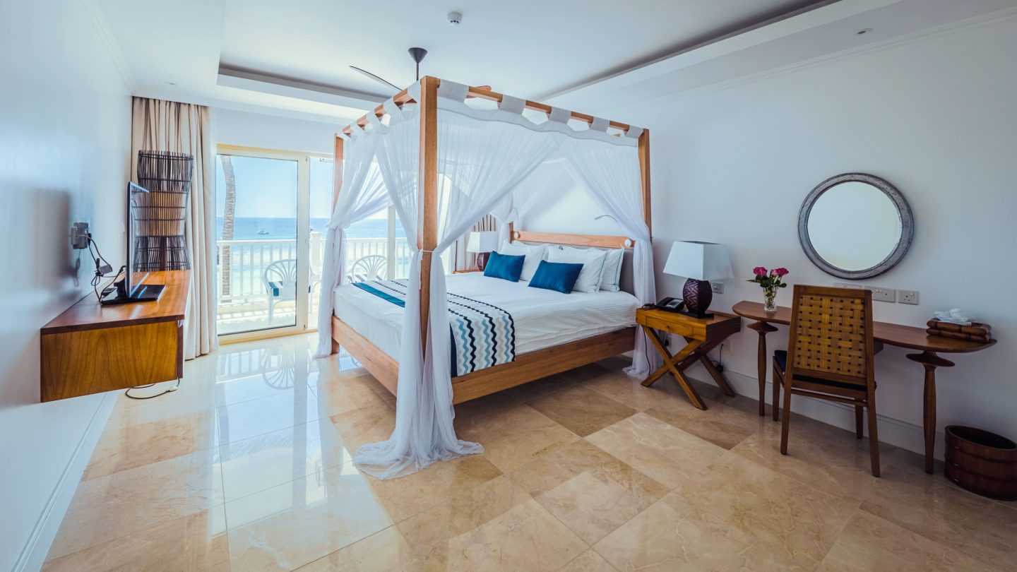 A light bedroom with a draped four-poster bed and pale floors