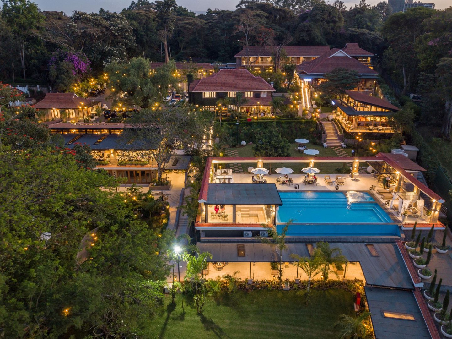 Lodge grounds and a lit pool after dark, seen from above