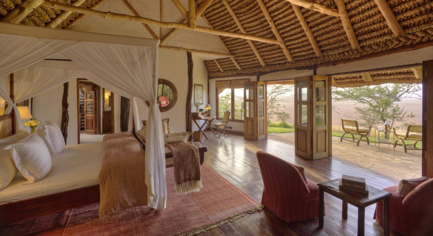 A cottage sitting room with soft furniture and doors open to the lawn