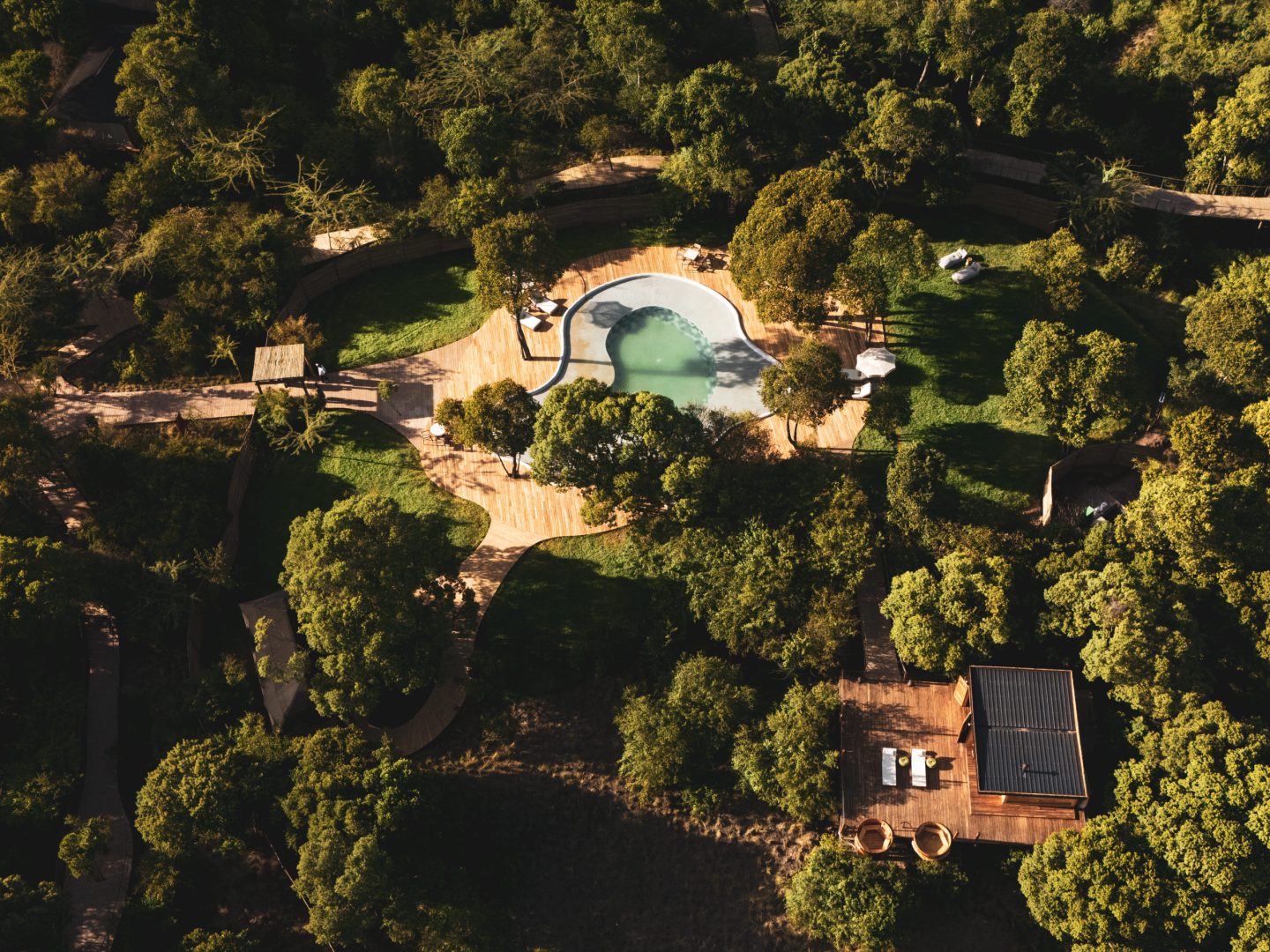 A lodge almost hidden in dense forest, seen from the air