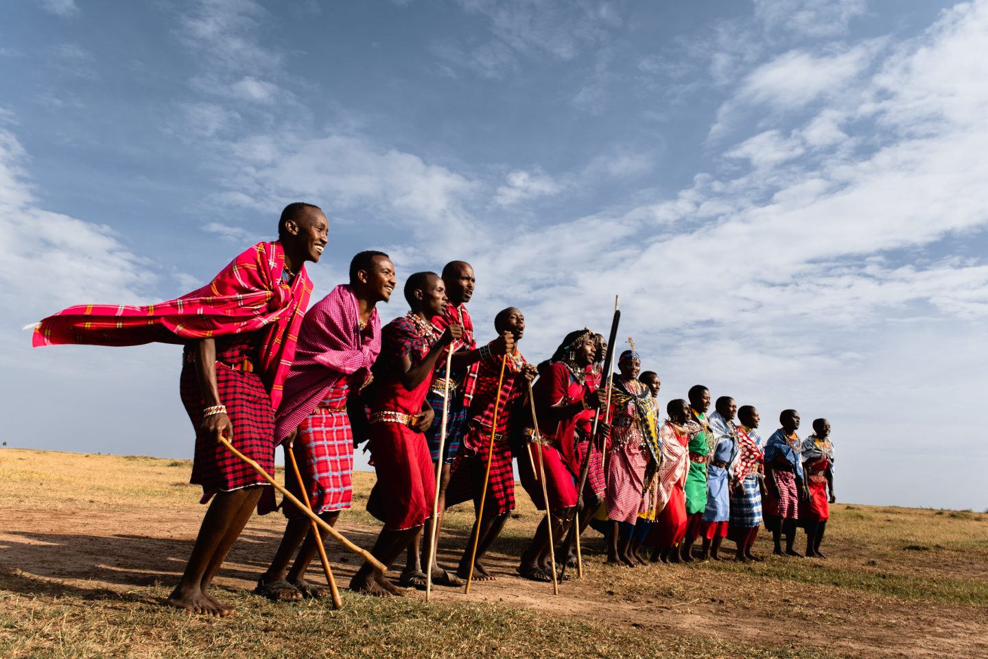 A line of Maasai men in red shukas standing on open grassland