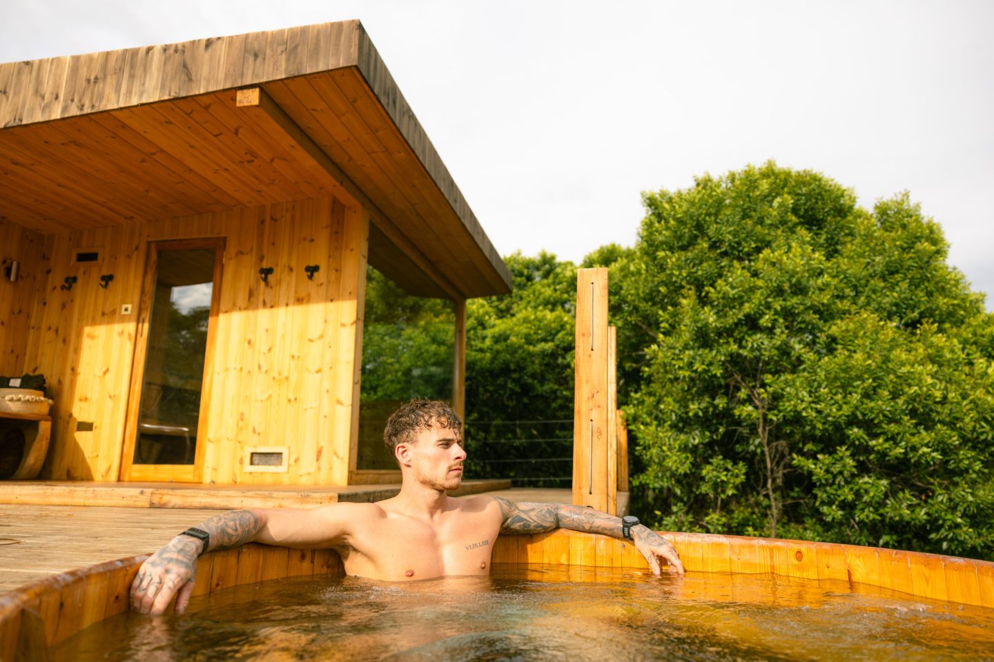 A guest relaxing in an outdoor bath with a drink to hand