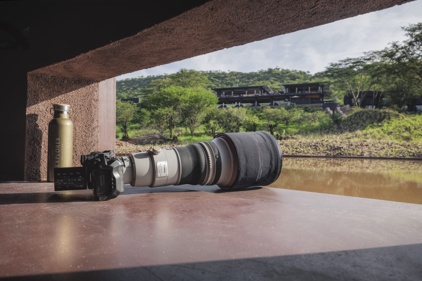 A long camera lens resting on a beanbag inside a photographic hide