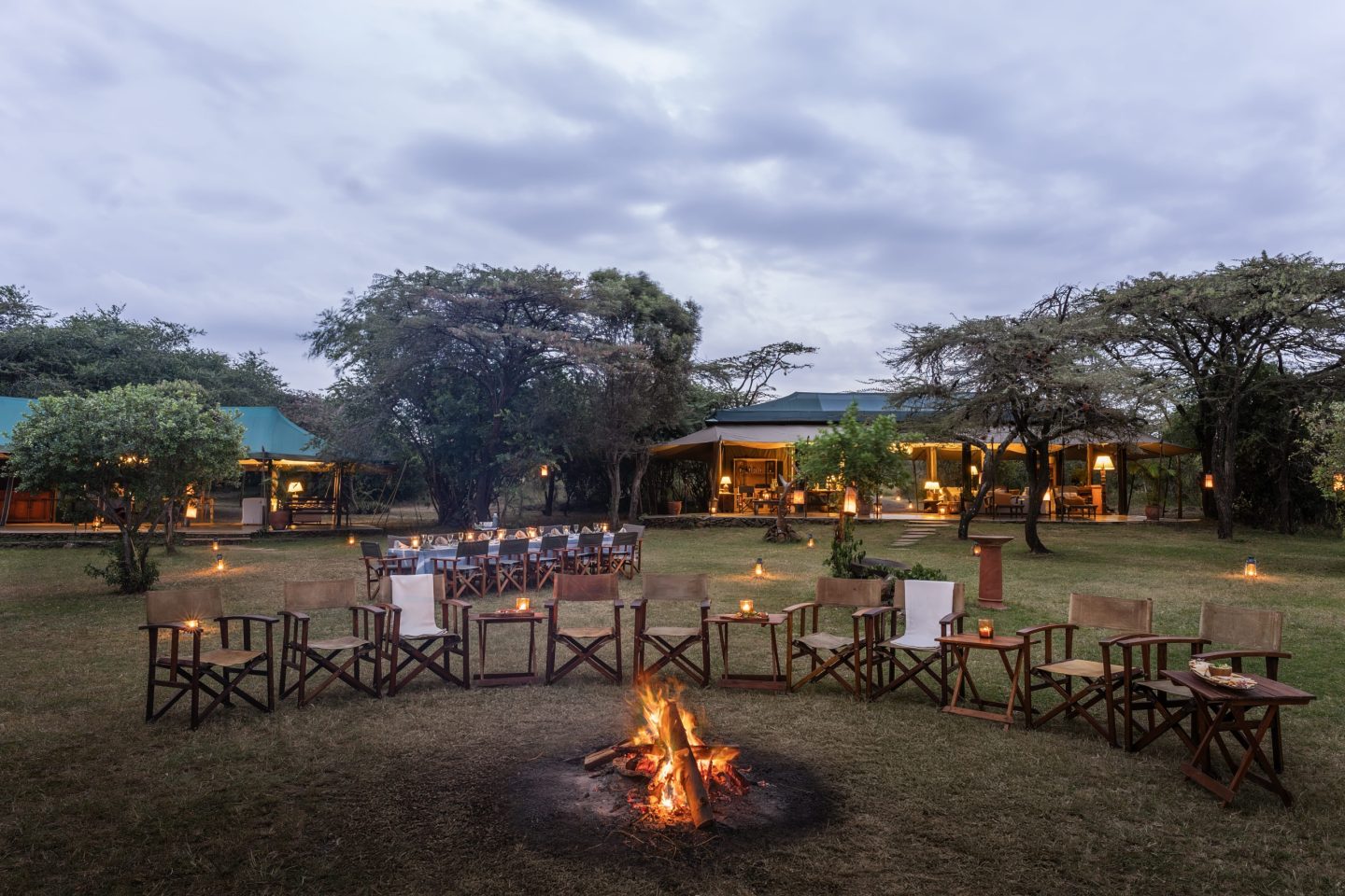 Camp chairs set around a fire on the plains as the sun goes down