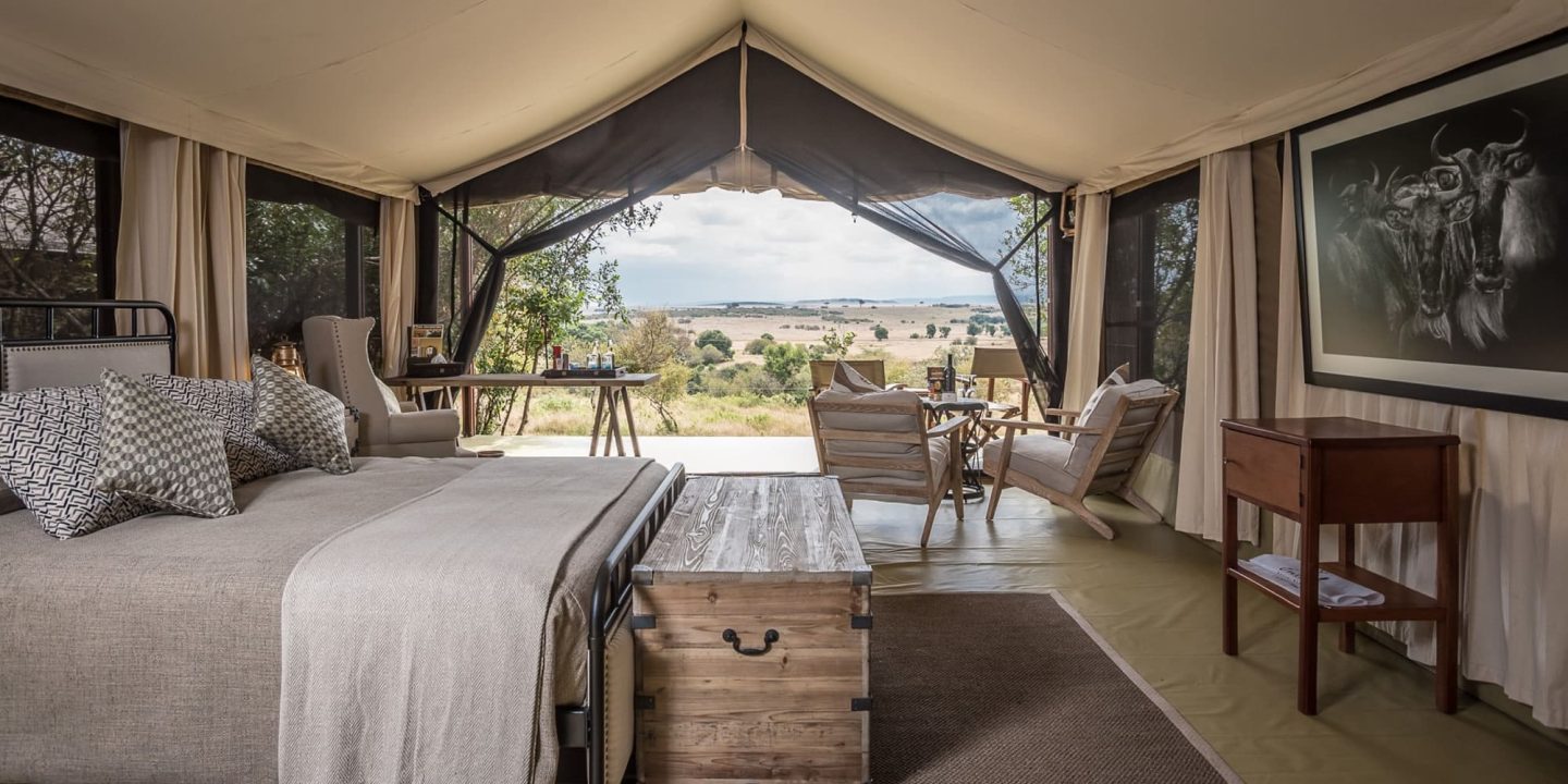A tent bedroom looking out across bush through a wide opening
